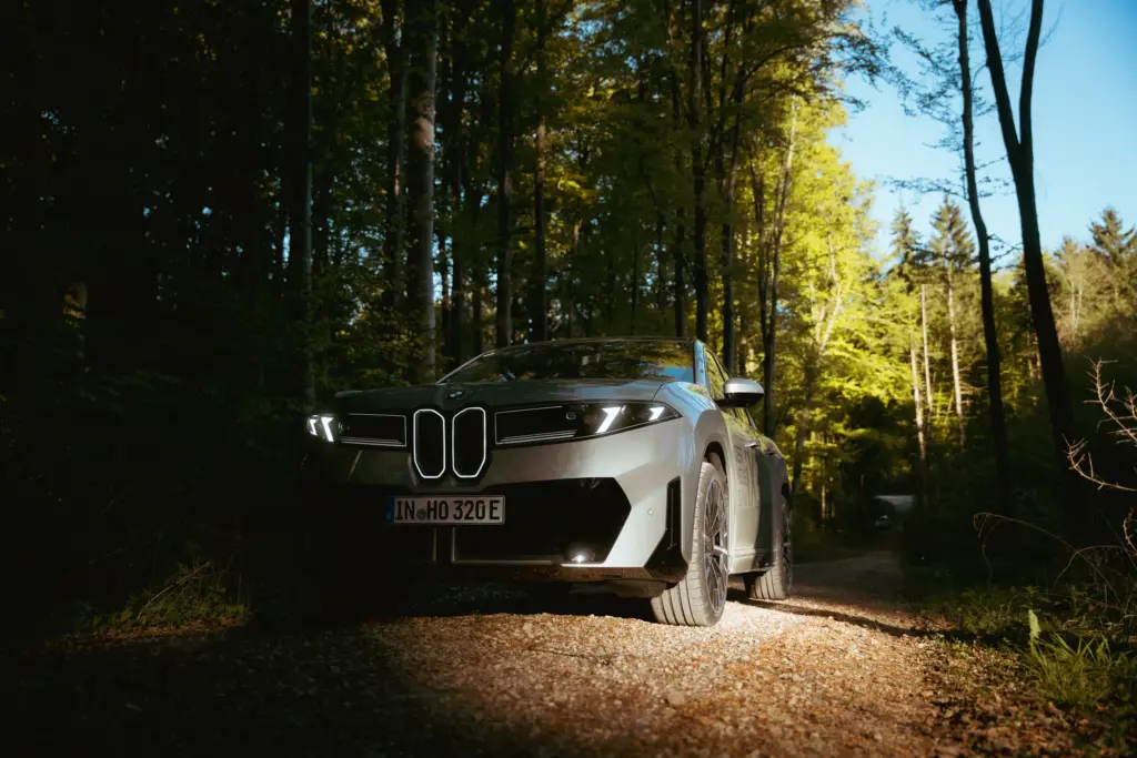 BMW iX3 zwischen Licht und Schatten im Wald