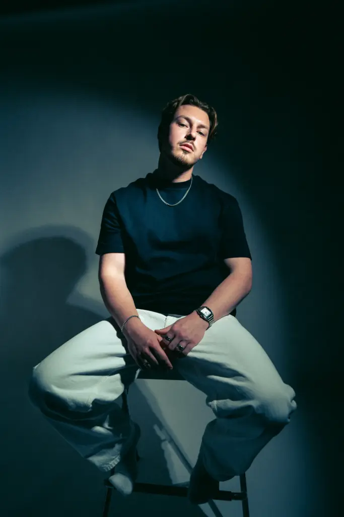 DJ Wamax auf einem Hocker im Spiel aus Licht und Schatten
