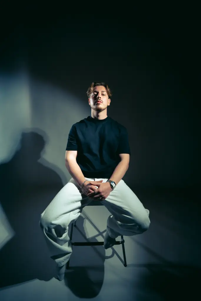DJ Wamax sitzend auf einem Hocker