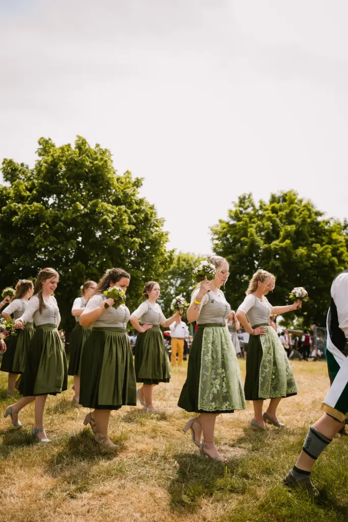 Frauen im Dirndl im Festzug über die Wiese