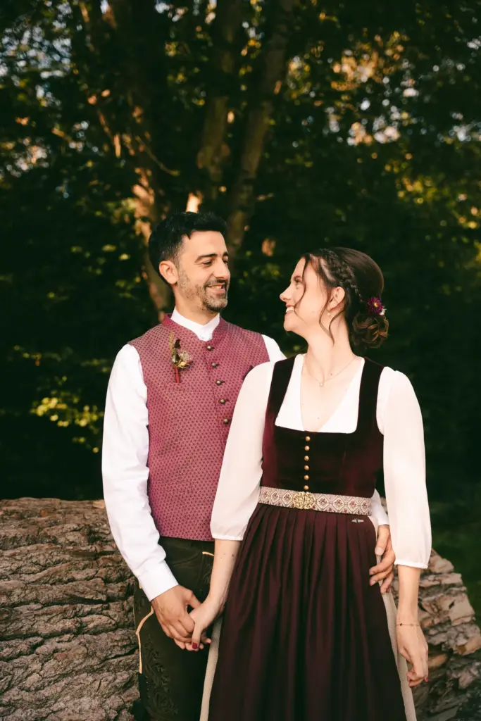 Brautpaar in Tracht lehnt an einem Baumstamm