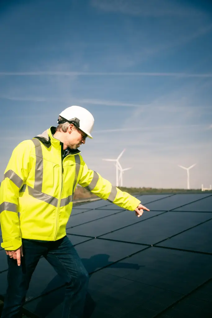Mitarbeiter mit Helm zeigt auf Solarmodule