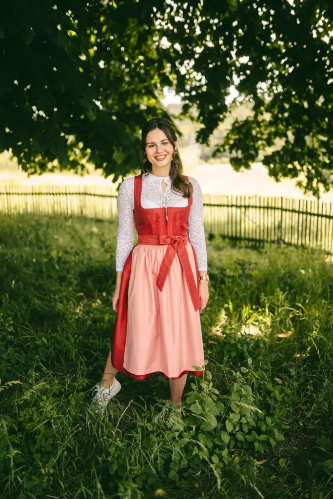 Frau im roten Dirndl auf einer Wiese, Shooting für Trachten Dieser